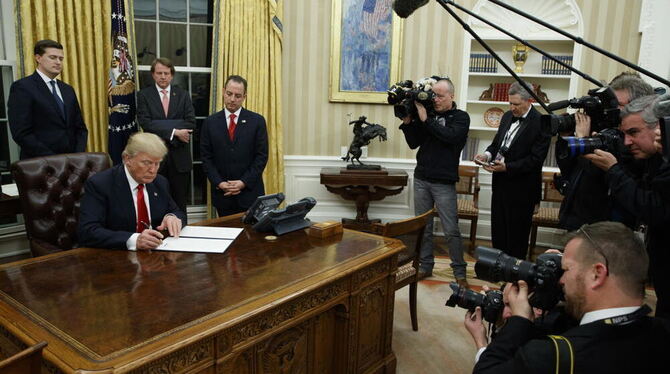 Umringt von Fotografen unterzeichnet der neue US-Präsident Donald Trump nach der Amtsübernahme seine erste Anordnung im Oval Off