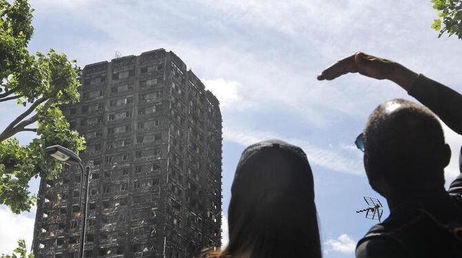 Ein Paar blickt zum ausgebrannten Grenfell Tower in London. Nach der katastrophe hat in mehreren Ländern die Debatte über bes