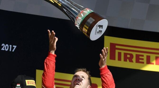 Sebastian Vettel vom Team Scuderia Ferrari wirft den Pokal nach seinem Sieg auf dem Hungaroring in die Höhe. Foto: Szilard Ko