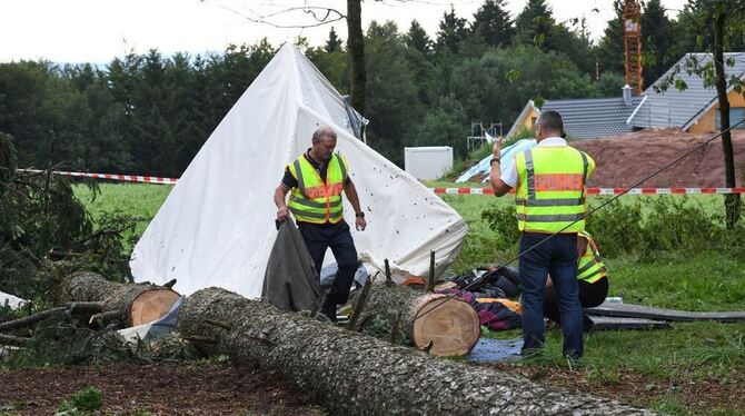 Polizisten nehmen ein beschädigtes Zelt auf dem Gelände eines Jugendzeltlagers bei Rickenbach in Augenschein.