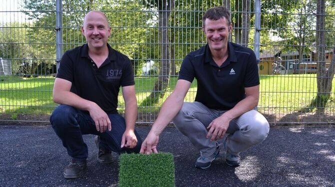 Axel Rieber (links) und Georg Frey vom Amt für Tiefbau, Grünflächen und Umwelt mit einem Muster des Kunstrasenbelags, der noch d