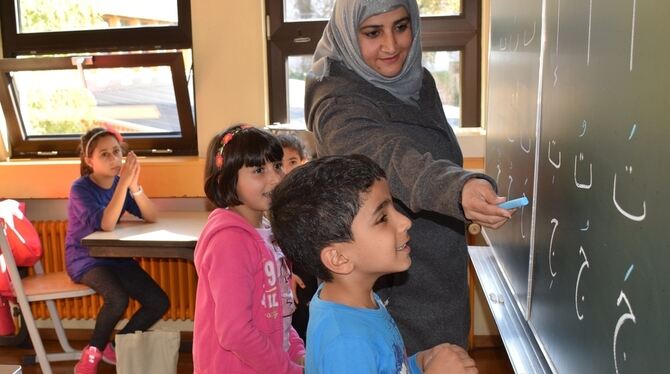 Lehrerin Nesrin Abdulwahed zeigt dem sechsjährigen Hassan und der achtjährigen Roha  Buchstaben der arabischen Schrift. Das late
