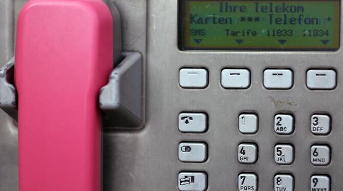 Ein magentafarbener Telefonhörer an einer Telefonsäule der Deutschen Telekom. Foto: Oliver Berg
