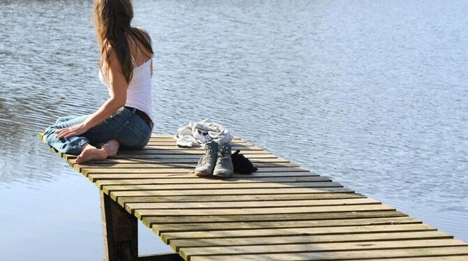 Eine junge Frau genießt an einem See in Niedersachsen das frühlingshafte Wetter. Foto: Ingo Wagner