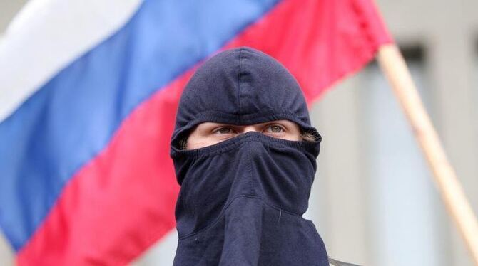 Ein maskierter Gegner der Regierung in Kiew posiert in Lugansk vor einer russischen Fahne. Foto: Zurab Kurtsikidze