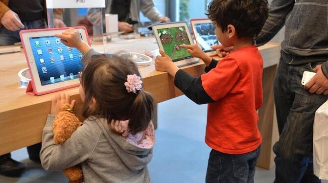 Ein Mädchen und eine Junge spielen im Apple Store in Berlin an iPads. Foto: Britta Pedersen/Archiv