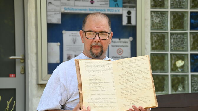 Der Vorsitzende des Schützenvereins Reicheneck, Wolfgang Tessmer, zeigt eine hand-geschriebene Vereins-Chronik.  FOTO: ZENKE