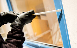 Ein Einbrecher auf Beutezug versucht mit einem Schraubenzieher ein Fenster aufzuhebeln.