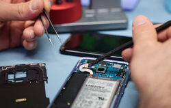 Ein Techniker repariert das Display eines Smartphones.