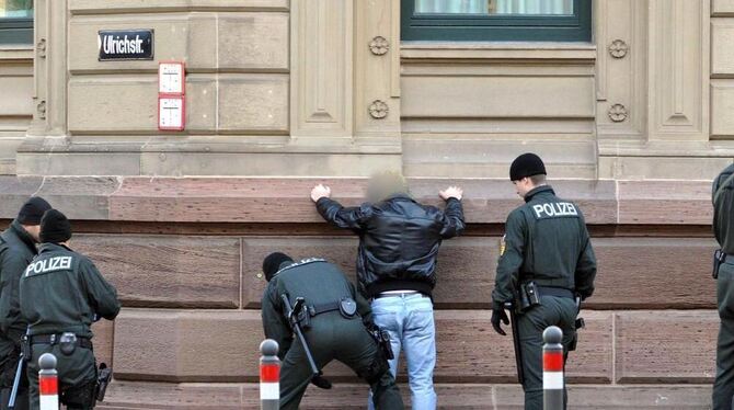 Ein Mann wird beim Rockerprozess an einer Straßenecke in der Nähe des Eingangs des Landgerichts Stuttgart von der Polizei kontro