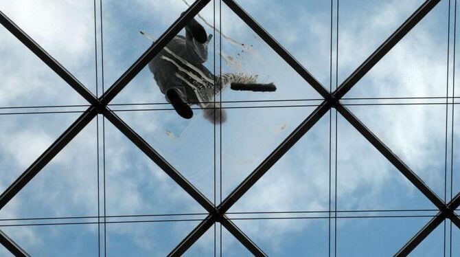 Ein Fensterputzer auf dem gläsernen Dach eines Geschäftshauses. Foto: Matthias Hiekel