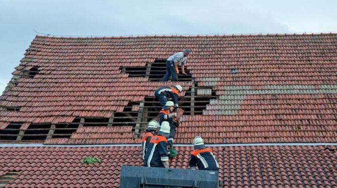 Feuerwehrmänner reparieren bei Freystadt in Bayern ein Dach, das durch eine Windhose beschädigt wurde. Foto: Daniel Karmann