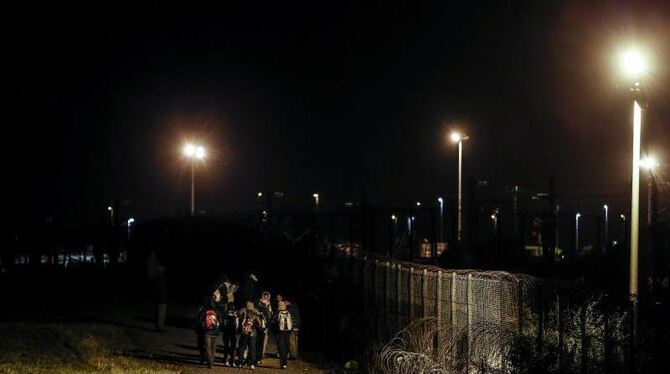 In Calais laufen Flüchtlinge entlang der Bahnstrecke, um einen Zug nach Großbritannien zu erwischen. Foto: Yoan Valat