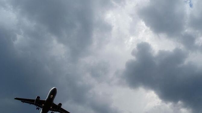 Gewitterwolken türmen sich über einem landenden Flugzeug auf. Schwere Turbulenzen könnten zur Mitte des Jahrhunderts mehr als