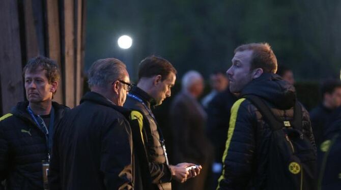 BVB-Trainer Thomas Tuchel (M) steht nach der Attacke auf den Bus mit seinem Team beisammen. Foto: Ina Fassbender