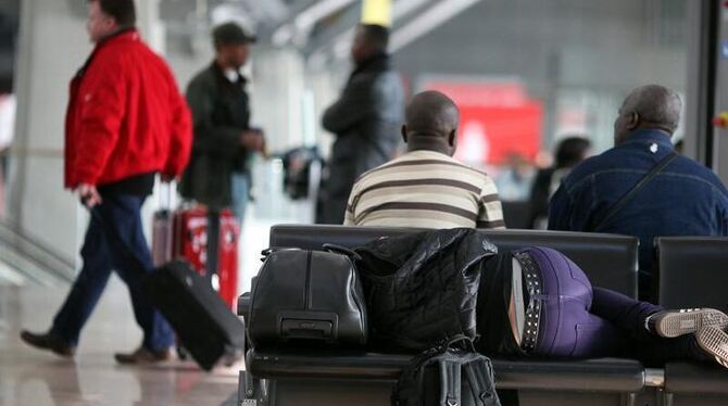 Passagiere schlafen im Hamburger Flughafen in der Wartezone auf Sitzbänken. 