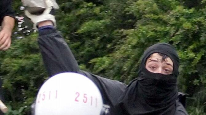 Ein Vermummter wirft während einer Demonstration einen Stein auf einen Polizisten. (Archivfoto).