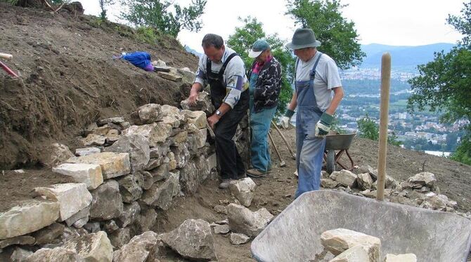 Arbeitsplatz mit schöner Aussicht: Bergwacht-Senioren ergänzen eine alte, wiederentdeckte Mauer mit neuen Steinen.