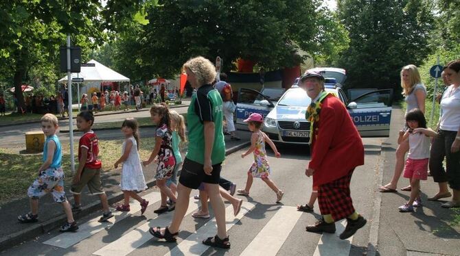 Polizeiobermeisterin Stephanie Reutter und Clown Clip bringen Kinder des Kinderhauses Nördlinger Straße in Orschel-Hagen sicher