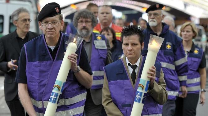 Notfallseelsorger tragen Kerzen zum Trauergottesdienst.