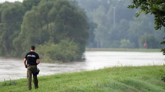 Ein Polizeibeamter geht über den Deich unweit der evakuierten Ortschaft Klein Bademeusel,.