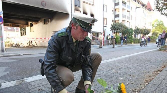 Ein Polizist legt vor dem Wohnhaus mit der ausgebrannten Wohnung der Amokläuferin eine Sonnenblume nieder.