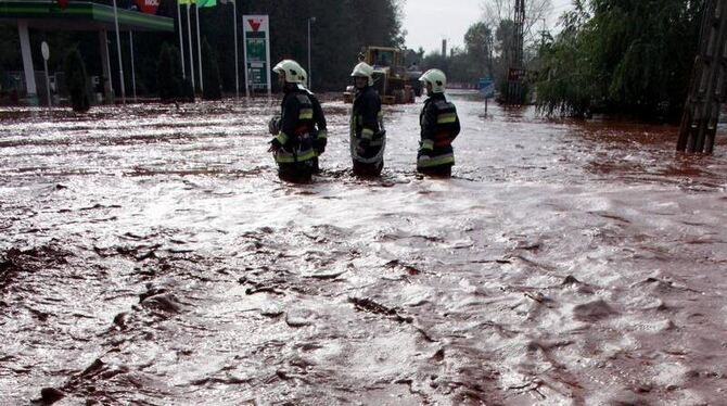 Feuerwehrmänner warten durch den Klärschlamm in den Straßen im ungarischen Devecser. Die Umweltorganisation WWF befürchtet ve