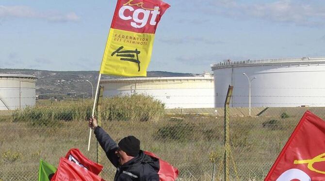 Ein mit einer Gewerkschaftsfahne bewehrter Demonstrant vor einer Raffinerie in Frankreich.