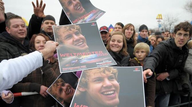 Ein Mann verteilt während des Empfangs Plakate mit einem Foto des Weltmeisters.