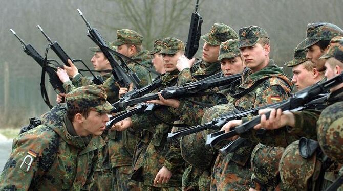 Ein Ausbilder der Bundeswehr überprüft auf einem Truppenübungsplatz die Waffen der Rekruten.