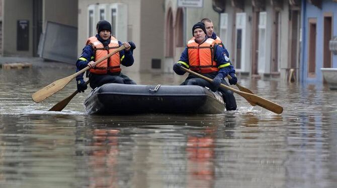 Mitglieder des Technischen Hilfswerks paddeln mit einem Schlauchboot durch die überflutete Altstadt von Wertheim (Foto vom 11