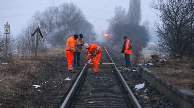 Bahnmitarbeiter untersuchen den Gleiskörper am Ort des Eisenbahnunglücks bei Hordorf.