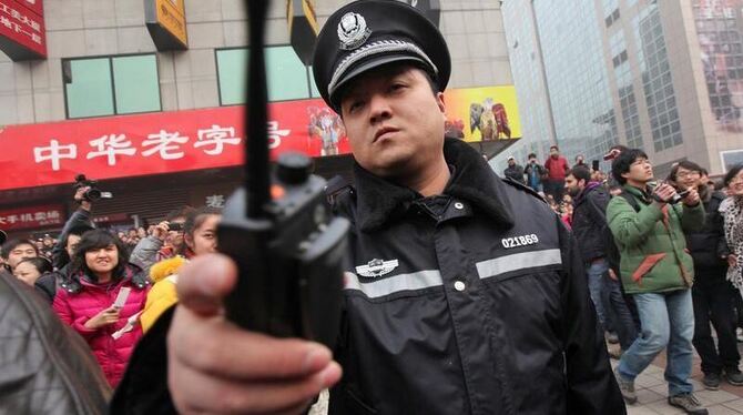 Ein chinesischer Polizist versucht Aufnahmen der Demonstration zu unterbinden.