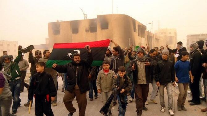 Regierungsgegner in der libyschen Stadt Tobruk halten eine Flage aus der Vor-Gaddafi-Ära bei einer Demonstration hoch.