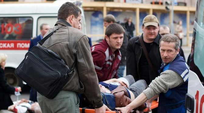 Rettungskräfte und Passanten tragen einen Verletzten in Minsk zu einem Rettungswagen. 