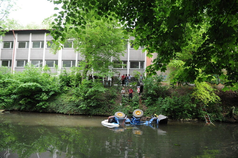 Kran zieht Baumaschine aus dem Neckar