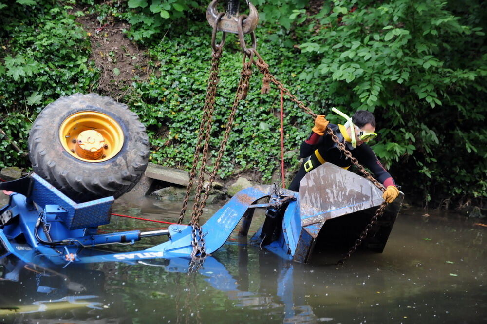 Kran zieht Baumaschine aus dem Neckar