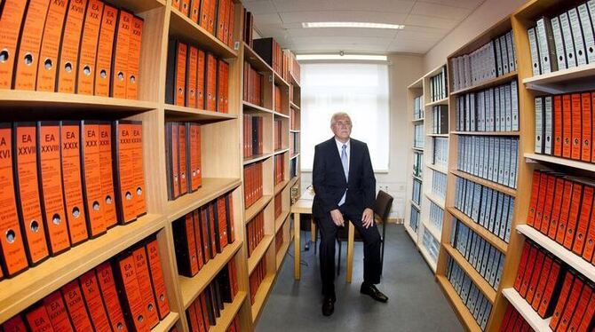 Klaus Scheuer, Präsident des Landgerichtes Frankfurt am Main, sitzt in einem Raum zwischen rund 600 Aktenordnern, die die Gru