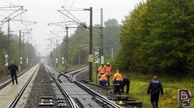 Polizisten und Mitarbeiter der Deutschen Bahn untersuchen bei Falkensee ein Leitungskasten an den Bahngleisen. Foto: Holger K