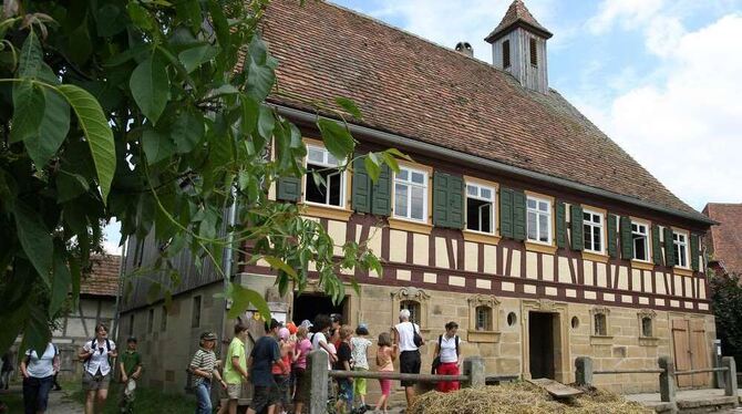 Ein Besuchergruppe betritt auf dem Gelände des Hohenloher Freilandmuseums in Wackershofen bei Schwäbisch Hall ein Wohn-Stall-Hau