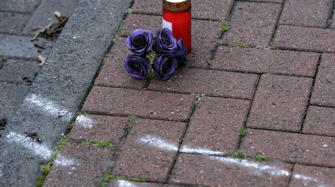 Blumen und eine Kerze stehen neben einer Kreideskizze auf einem Bürgersteig im niedersächsischen Stolzenau. Foto: Alexander K