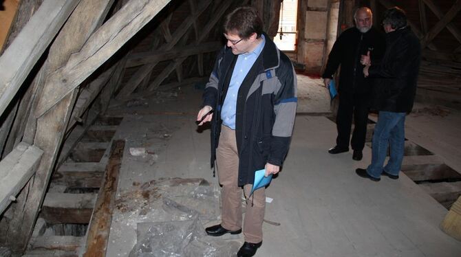 Architekt Dieter Schmid begutachtet die Schäden am Dachstuhl der Martinskirche. Im Hintergrund diskutieren Dekan Michael Scheibe