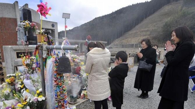 Angehörige von Opfern des Tsunami trauern an der Stelle, wo eine Schule vom Tsunami getroffen wurde. Foto: Kimimasa Mayama