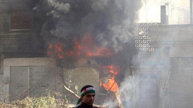 Ein Mann steht vor einem brennenden Gebäude in Homs (Syrien). Foto: LCC