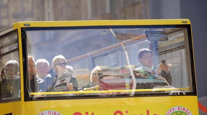 Touristen nutzen in Berlins Mitte am Checkpoint Charlie die Sonne in Berlin zu einem Ausflug mit einem Cabrio-Bus. Berlin ist