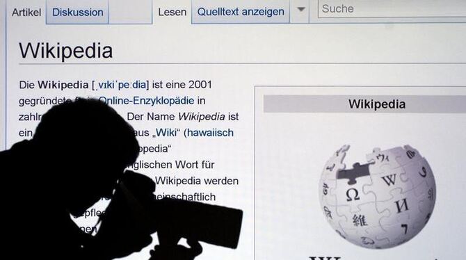 Die Silhouette eines Fotografen vor der Wikipedia-Webseite.