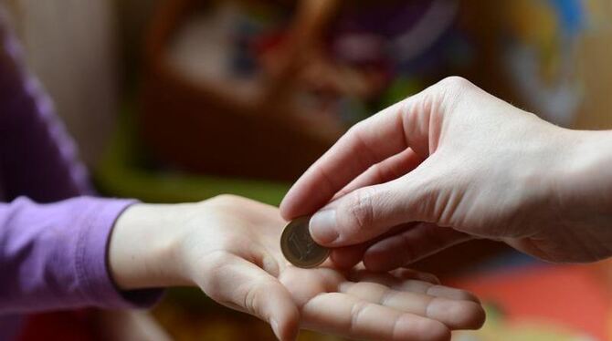 Ein Mädchen erhält von der Mutter einen Euro Taschengeld. Foto: Jens Kalaene