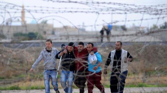 Noch 100 Meter zur türkischen Grenze: Syrer auf der Flucht stützen einen verletzten Freund. Foto: Veli Gurgah/Anadolu Agency