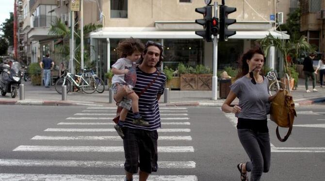 Flucht in Tel Aviv: Ein junges Elternpaar läuft nach dem Luftalarm in Richtung eines Schutzraums. Foto: Abir SUltan