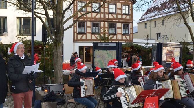 Weihnachtsmarkt in Dettingen: Der Harmonikaclub spielt, Bürgermeister Michael Hillert und der Vorsitzende des Gewerbevereins, Dr. Rolf Hägele (von links), singen kräftig mit. FOTO: SANDER